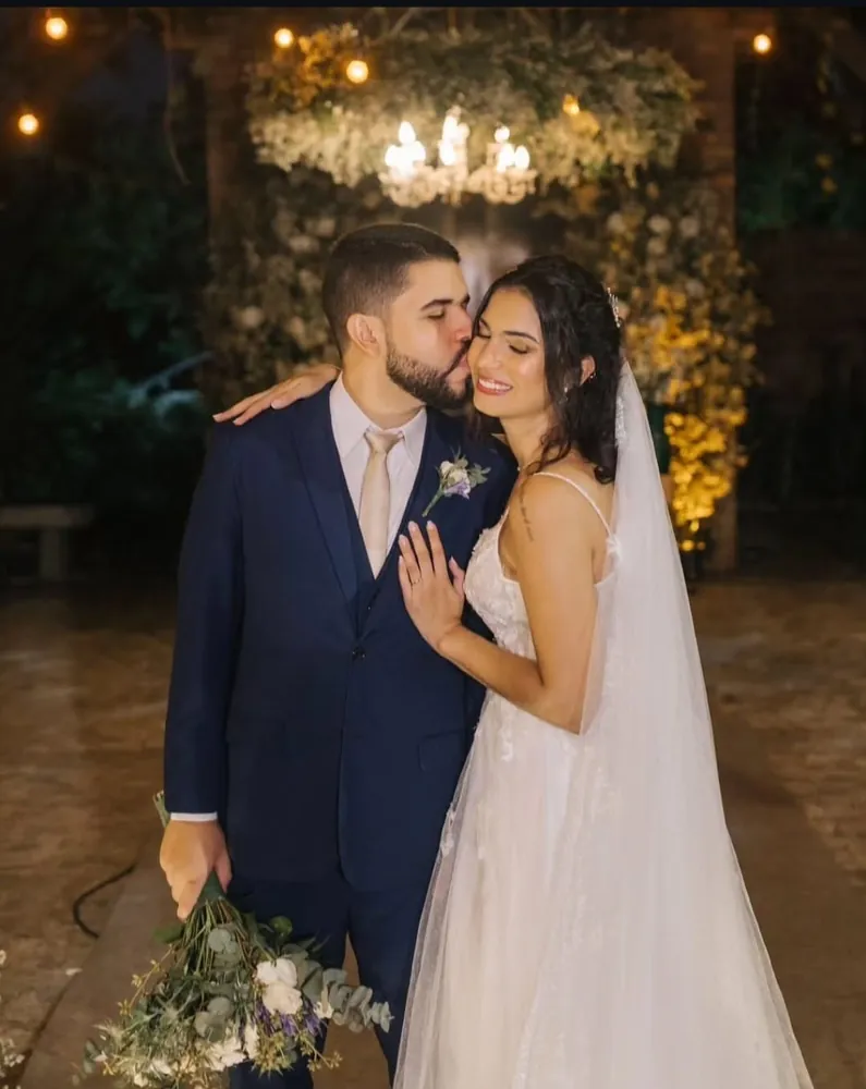 Casamento à noite — noivos sob lustre e flores